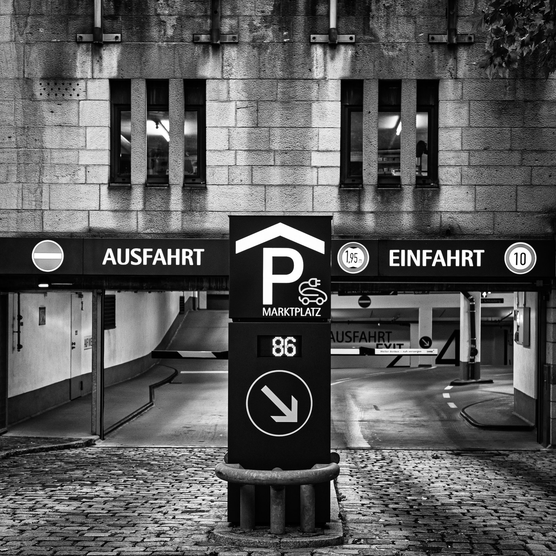 black-and-white parking garage entrance and exit with German signs and cobblestone forecourt