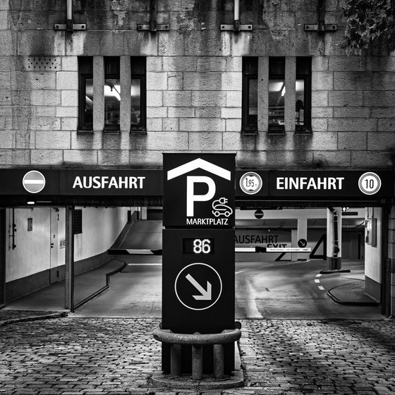 black-and-white parking garage entrance and exit with German signs and cobblestone forecourt